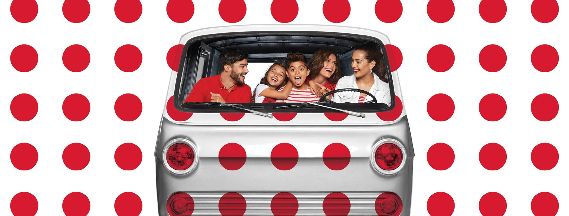 Beautiful family in retro van covered in red polkadots and white background.